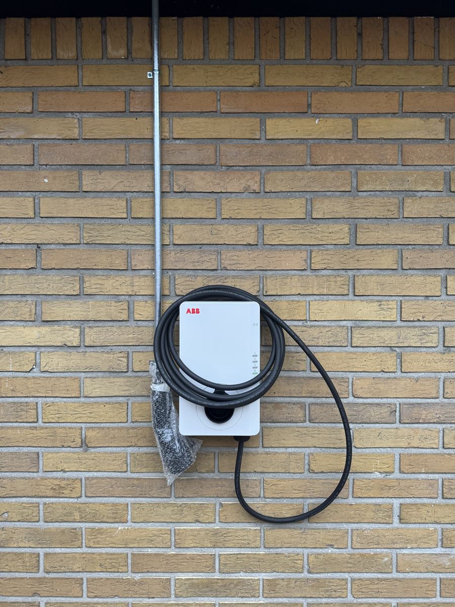 ABB EV charger mounted on a brick wall with the supply cable in galvanized conduit